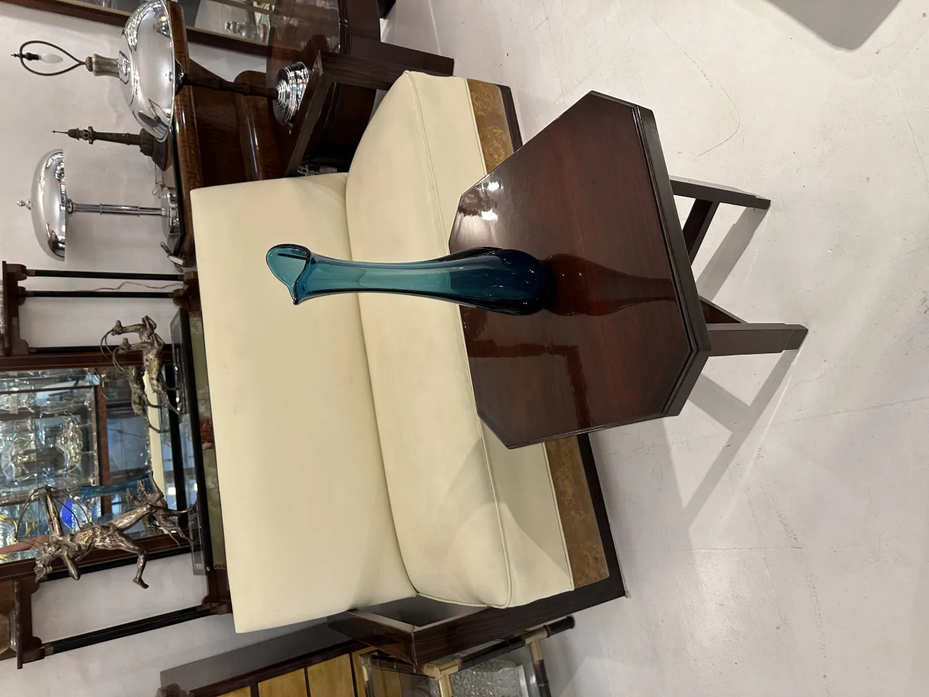 Florero antiguo de cristal sobre una mesa con fondo de muebles.