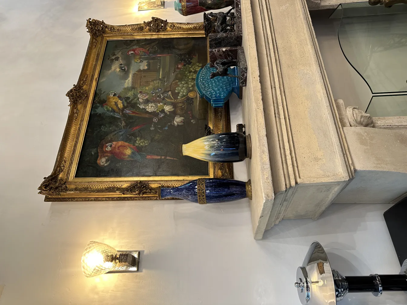 Antique decorative bookends with elegant design beside a colorful painting and other decorative items.