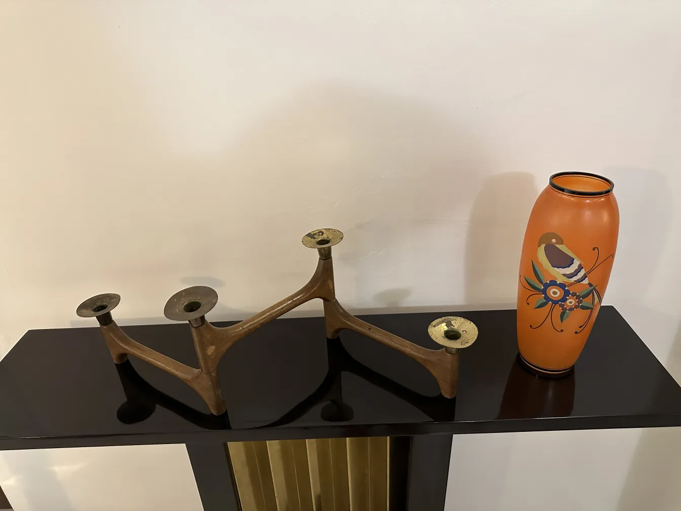 antique vase in orange tones decorated with colorful designs, alongside a candle holder