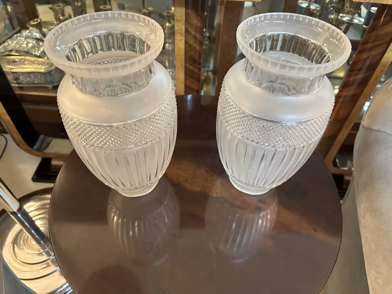 два античных вазона с декоративными деталями сверху, на элегантном столе