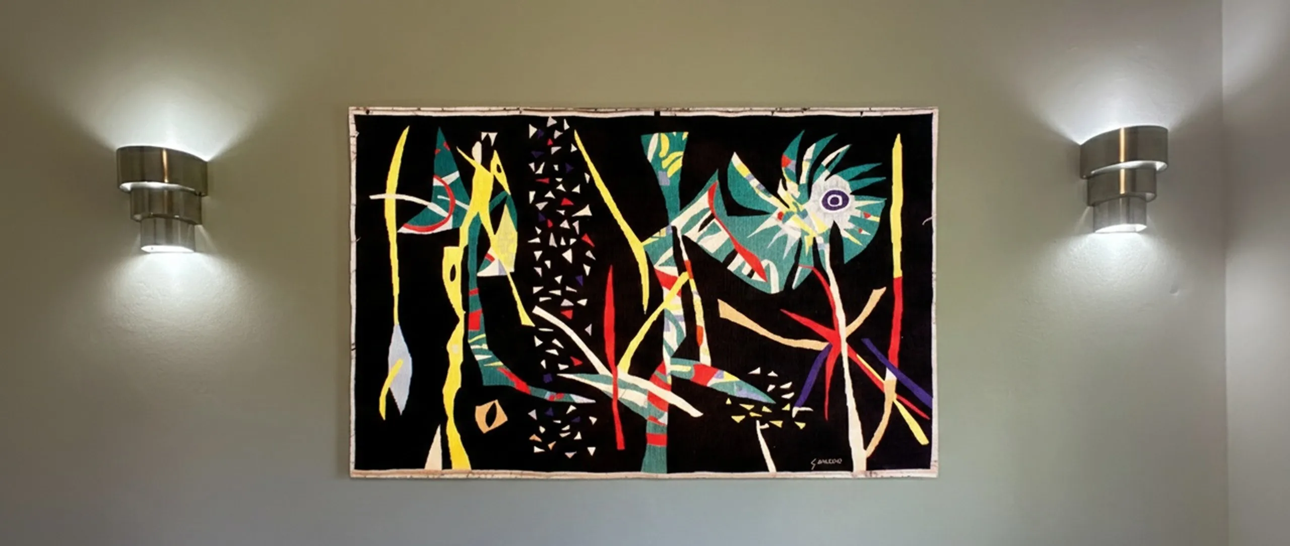 Par de luminárias de parede antigas com uma pintura colorida atrás.