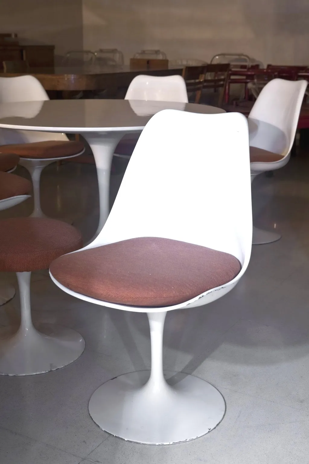 mesa de jantar antiga para sete pessoas em ambiente acolhedor com cadeiras brancas.