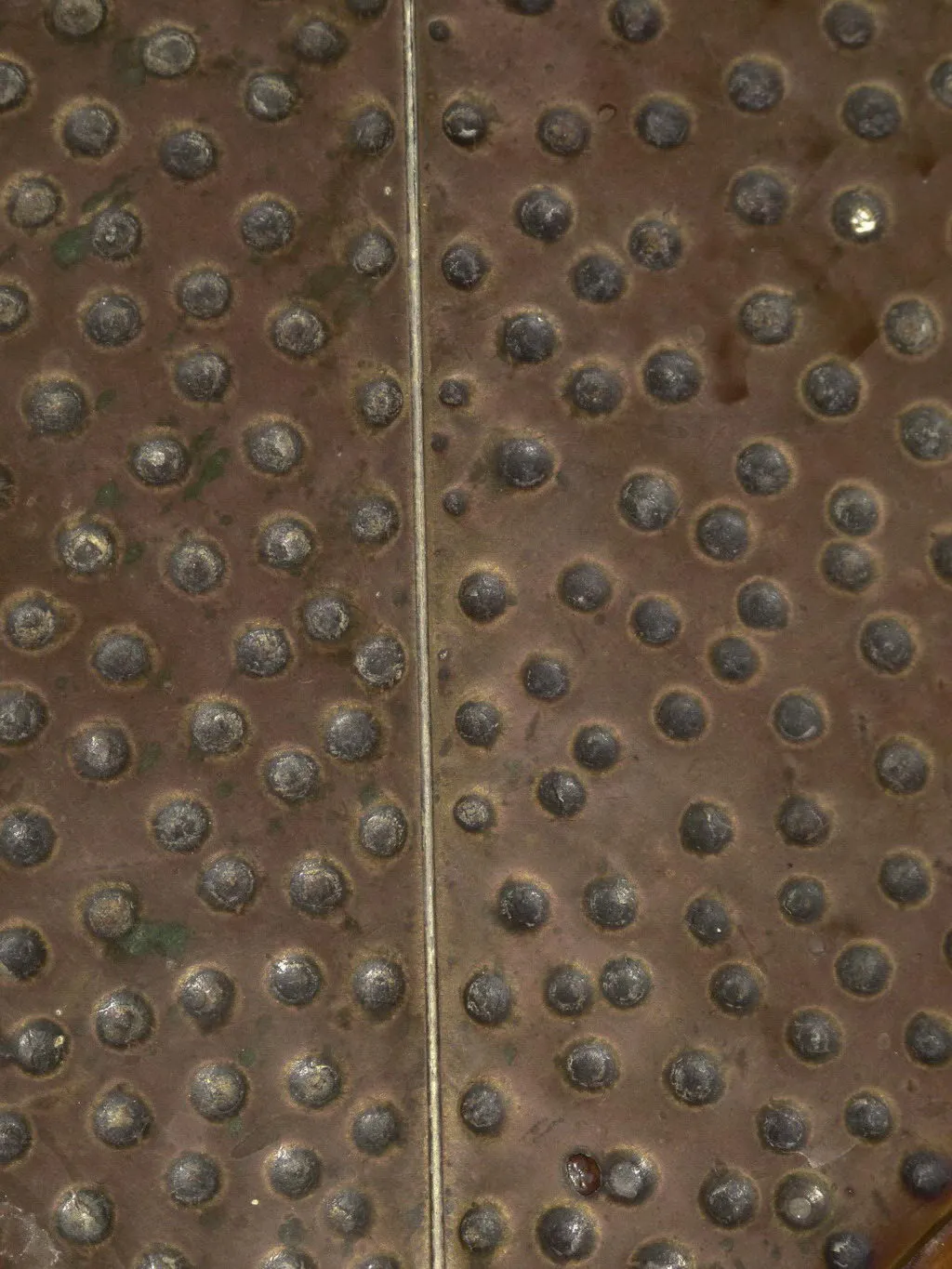 Tavolo da pranzo antico con ribattini, atmosfera accogliente.