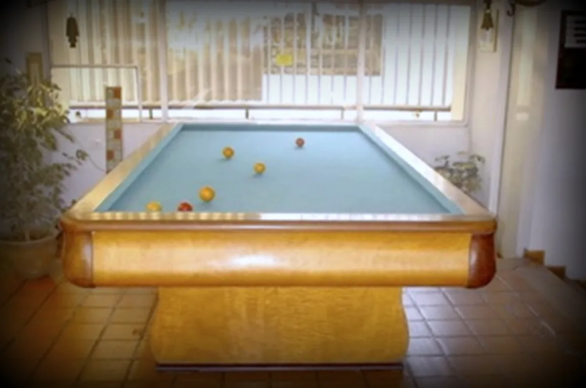 mesa de billar antigua con un tapete azul y bolas en la superficie