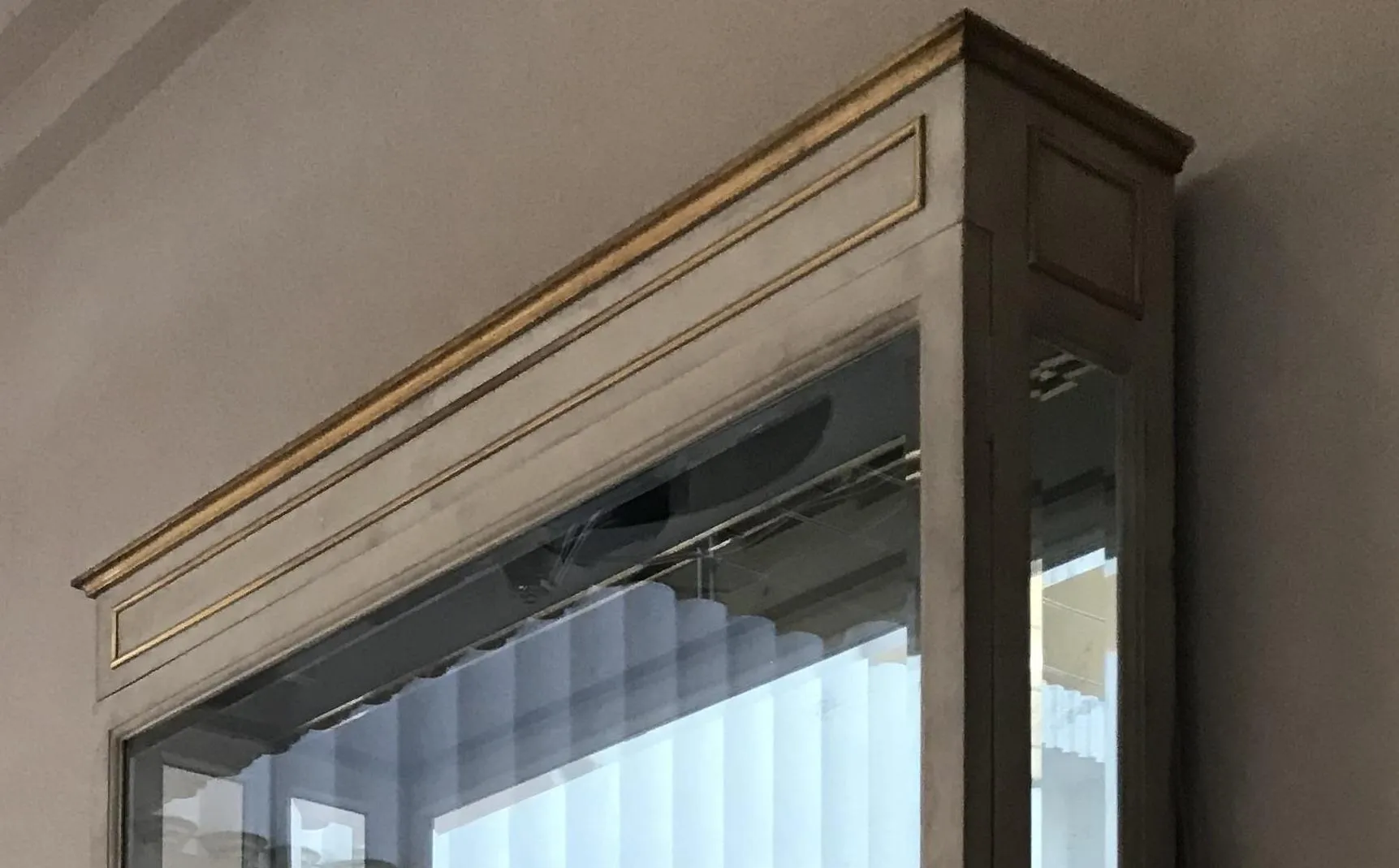 antike vitrine mit dekorativen details oben, in einer ausstellungsartigen umgebung.