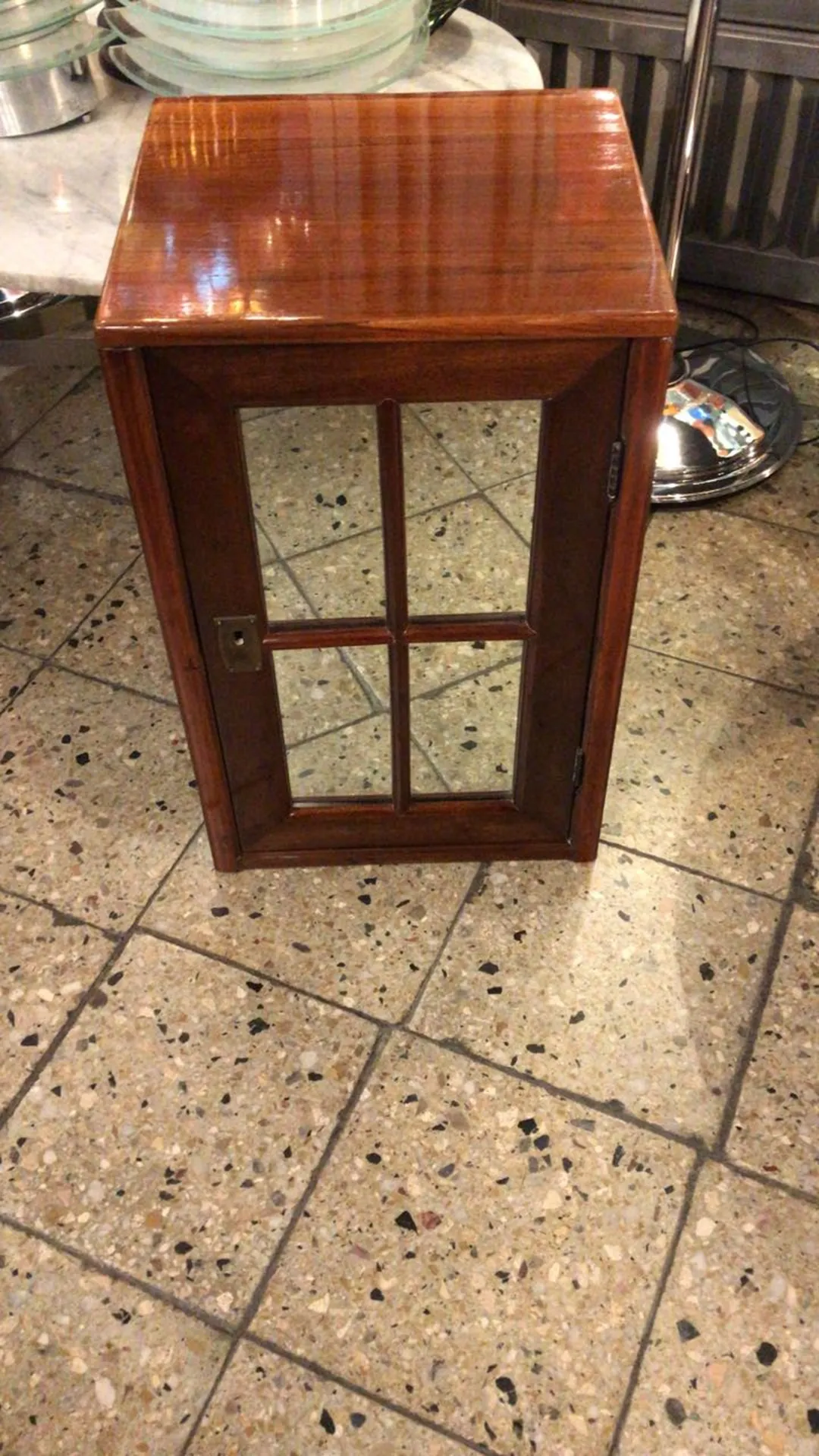 mesa de luz antiga com porta de vidro, situada em um piso de cerâmica