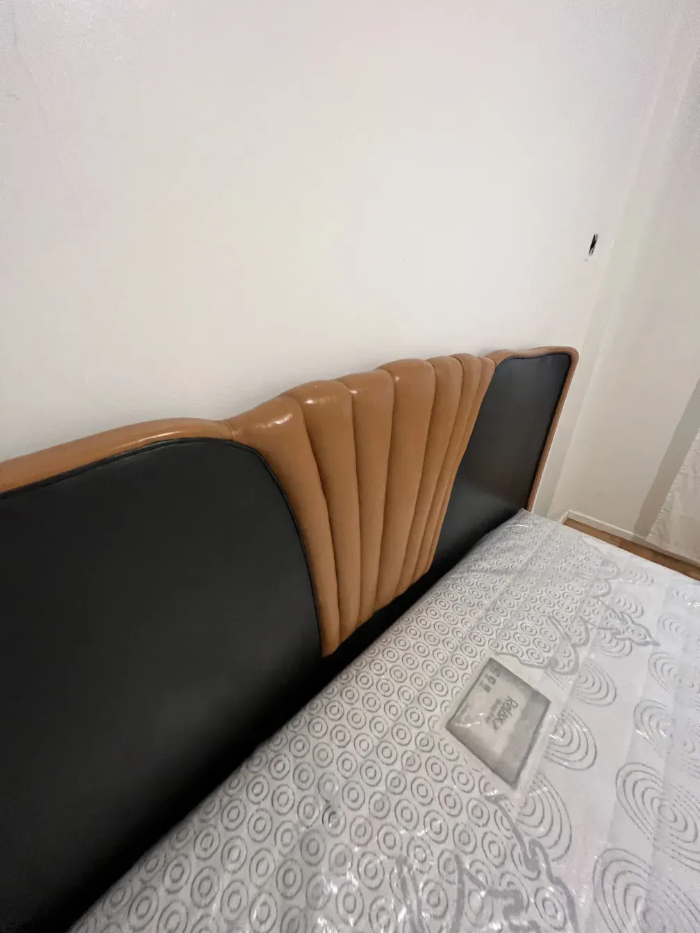 Cama antigua de estilo Art Deco con cabecera decorada en tonos claros y oscuros.