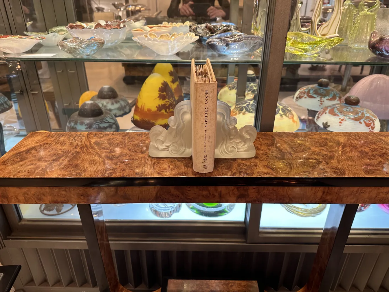 Art Nouveau bookends on a wooden table, decorative items in the background