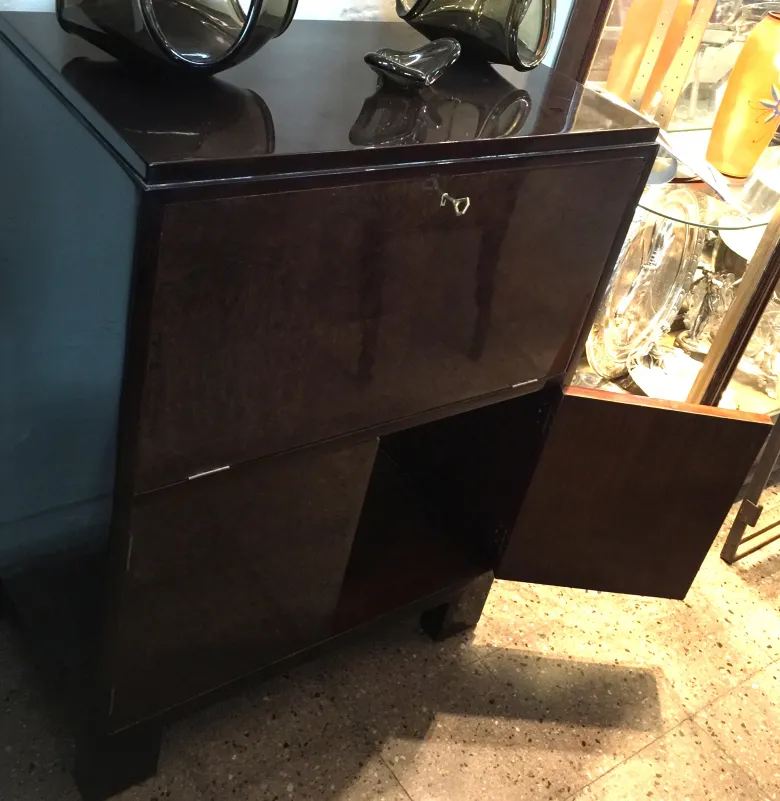 Meuble à cocktail antique avec surface brillante et fond sombre.