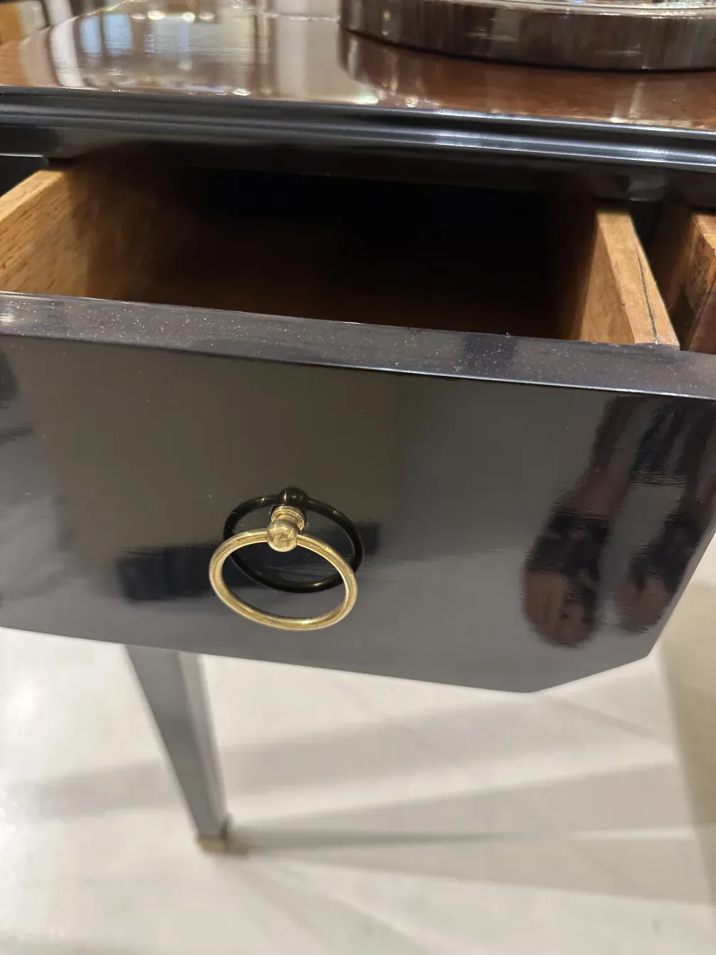 Antique desk with a shiny black finish and a gold handle. Elegant atmosphere.