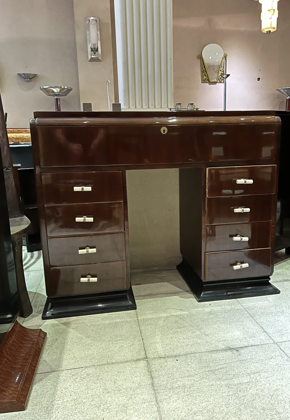 Antica consolle con più cassetti e dispenser in un ambiente decorativo.