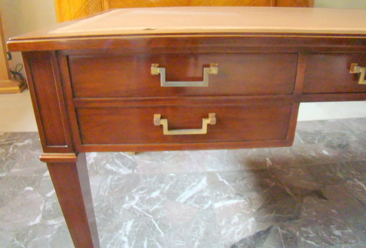 antique desk with two drawers and gold handles in a classic setting