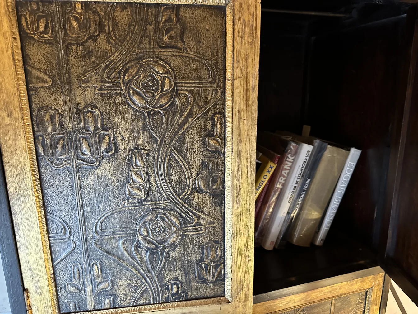 Bar antigo de madeira com detalhes em relevo e livros dentro.