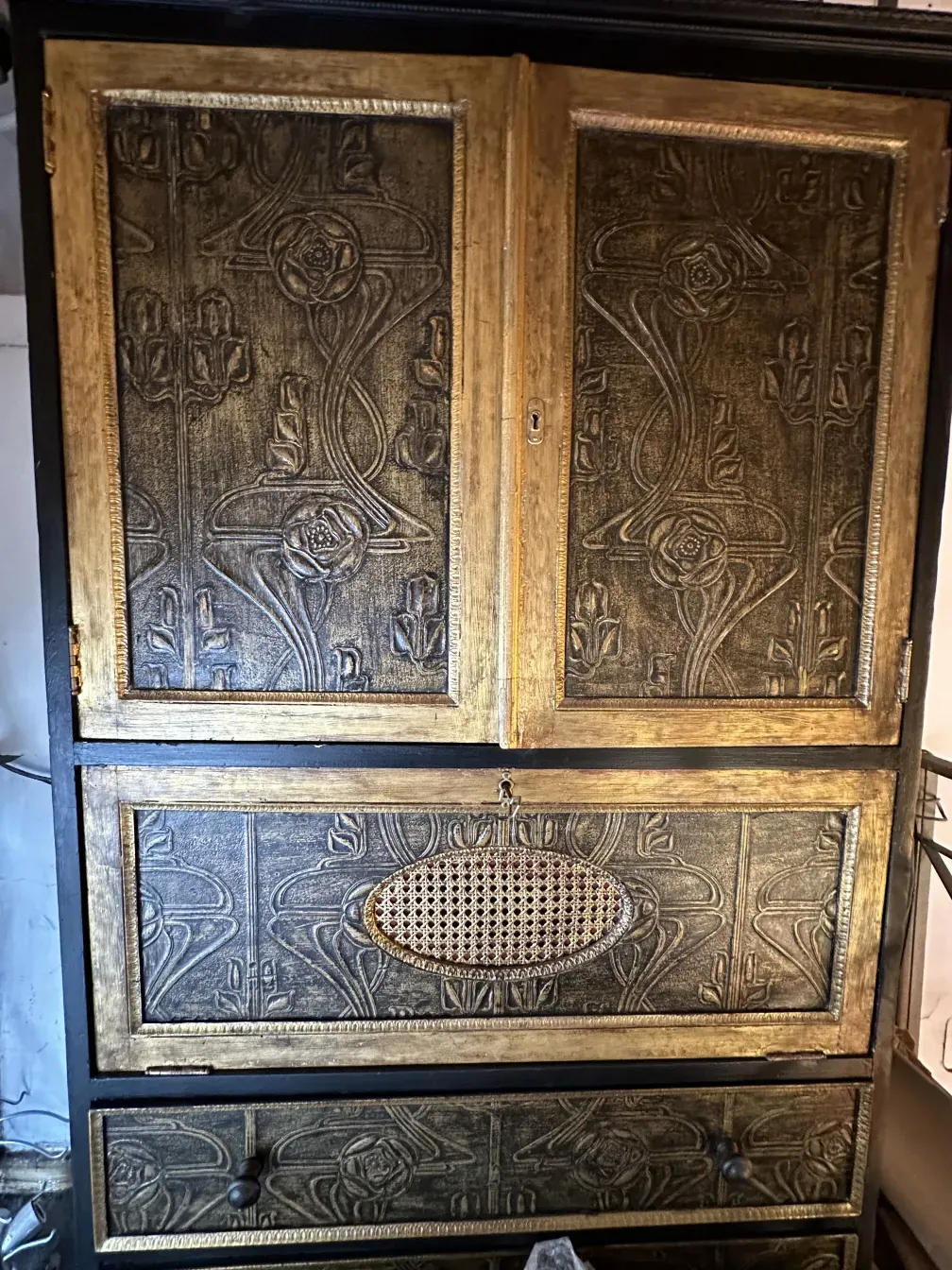 Mueble bar antiguo de madera con detalles en relieve dorado y negro.