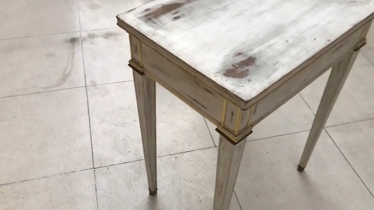 Escritorio antiguo blanco con patas delgadas en ambiente claro.