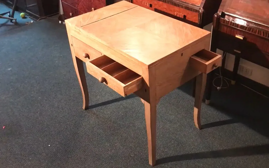 Scrivania antica in legno chiaro con due cassetti visibili.