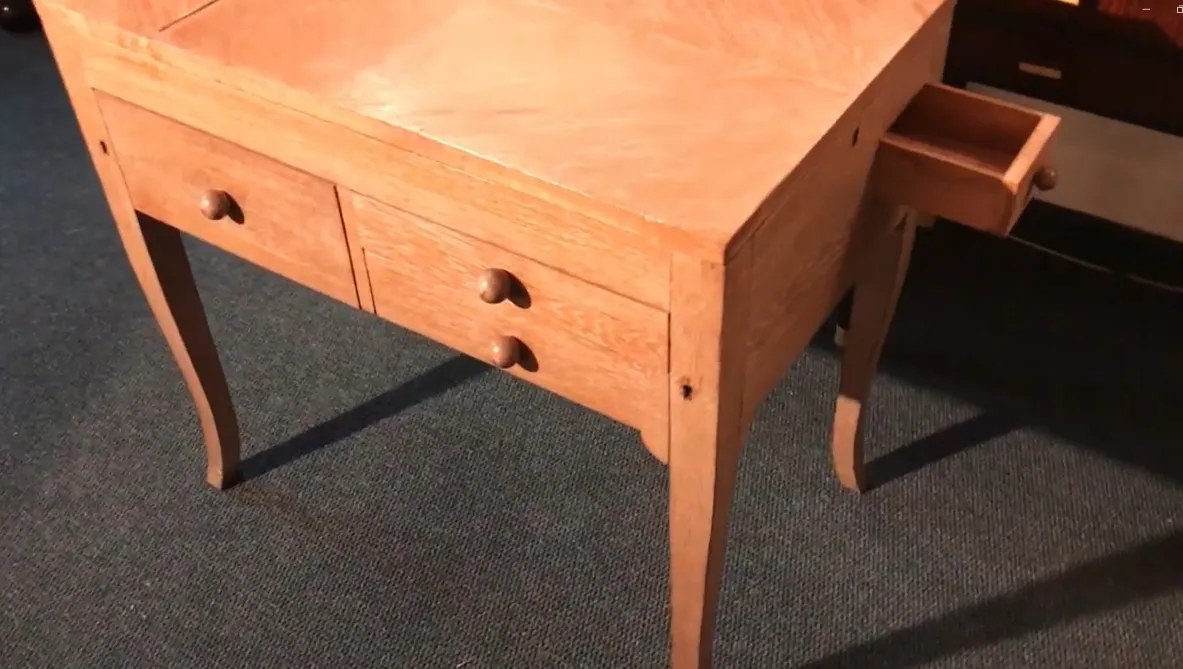 bureau ancien en bois clair avec deux tiroirs, sur fond bleu