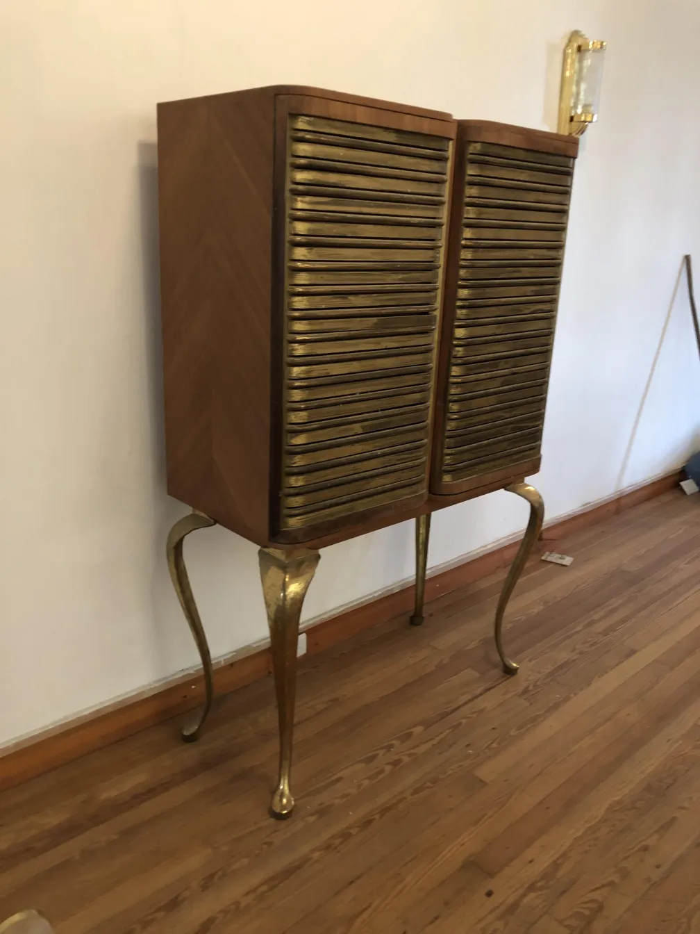 Meuble à cocktail ancien avec des détails dorés et des pieds élégants dans un cadre accueillant.