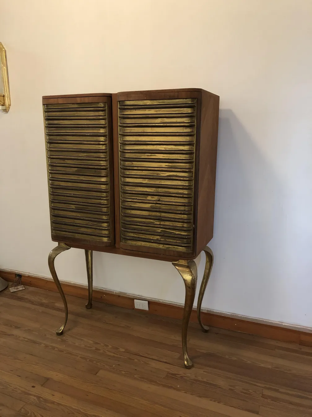 Armário bar antigo em madeira com portas douradas e pernas elegantes.