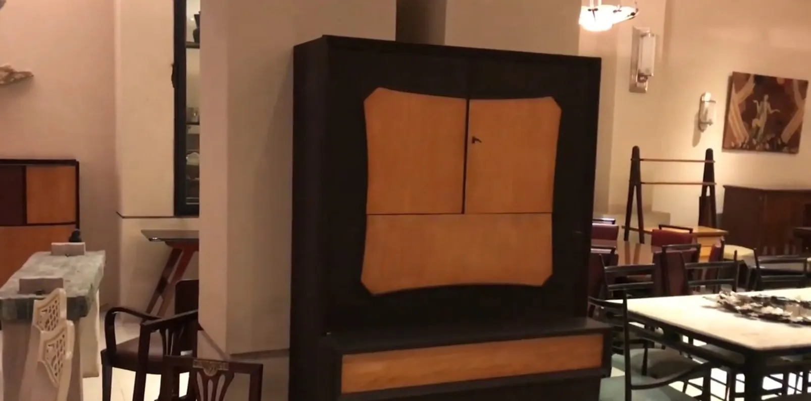 Mueble bar antiguo con acabado en colores cálidos, rodeado de mobiliario.