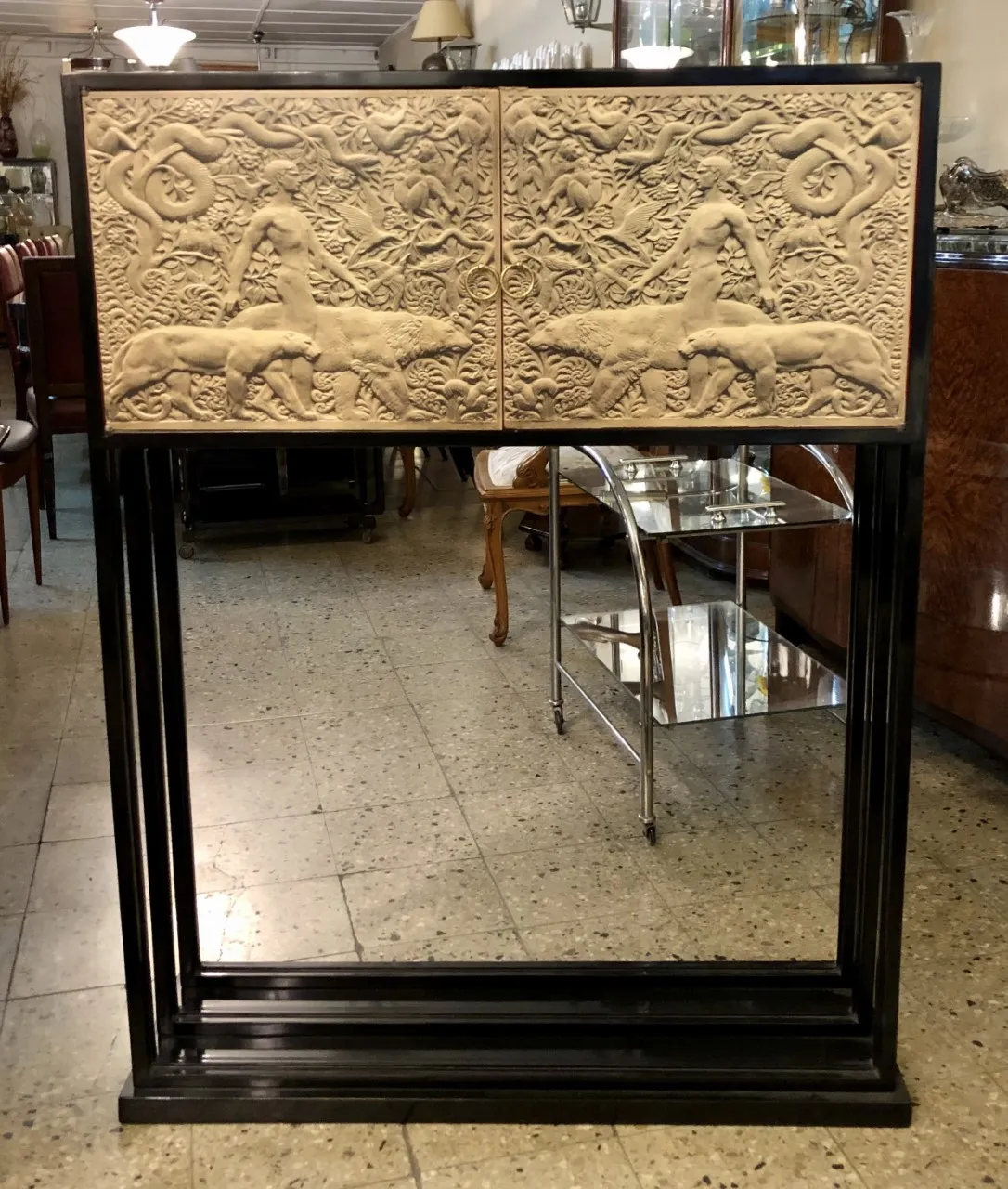 Mueble bar antiguo con relieves detallados de animales y hombre, ambiente acogedor.