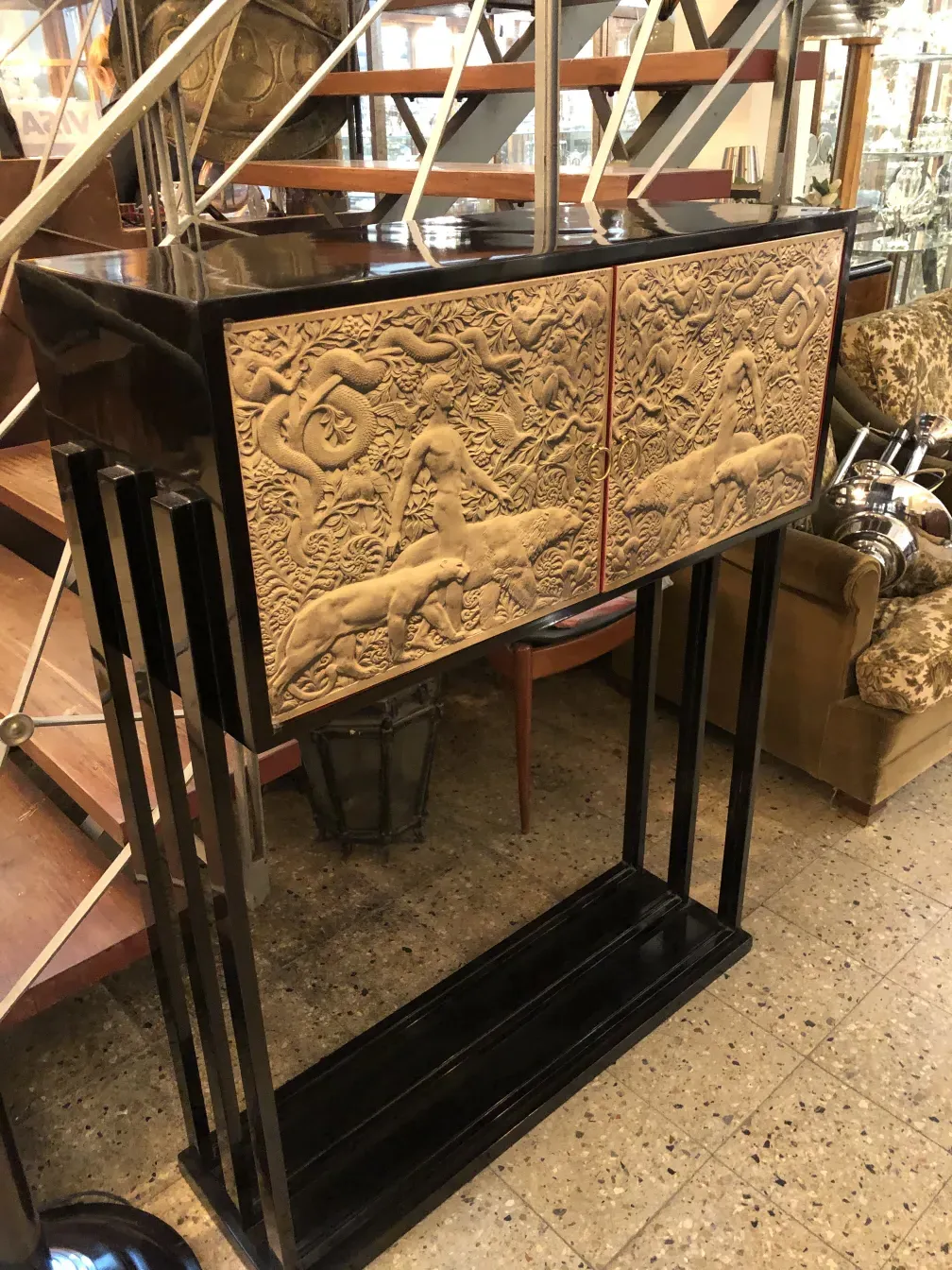 Antiguo mueble bar con detalles en relieve, fondo neutro.