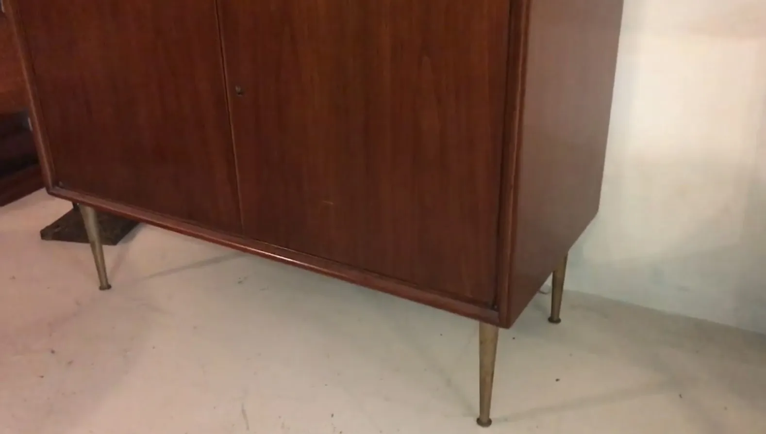 Antique wooden bar cabinet with stylish legs in a classic setting.