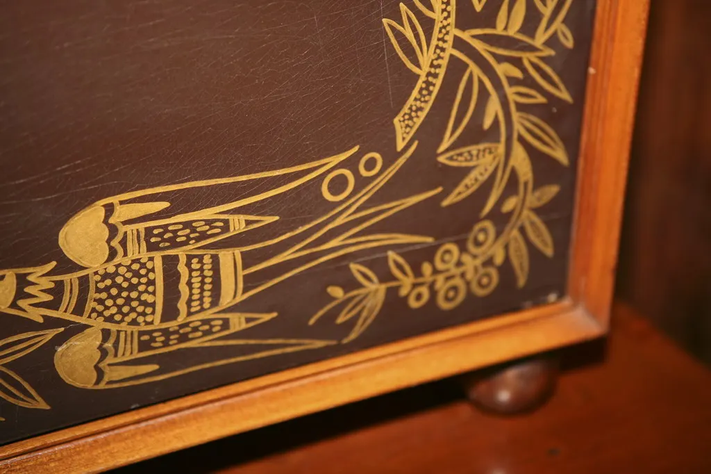 Antiker Cocktailschrank mit goldenem Blumendesign auf dunklem Hintergrund.