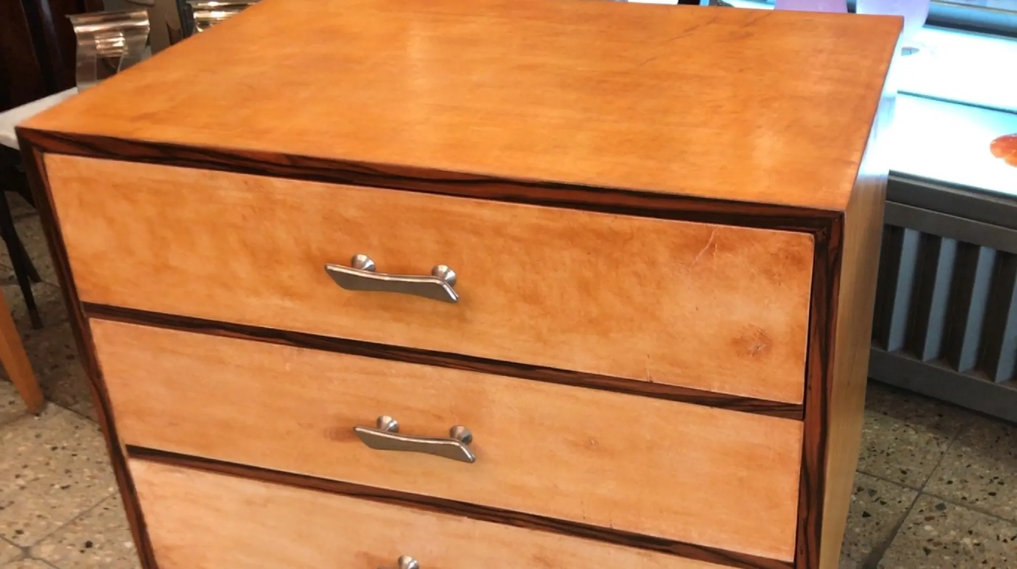 Antico comodino con cassetti e design pulito, atmosfera classica.