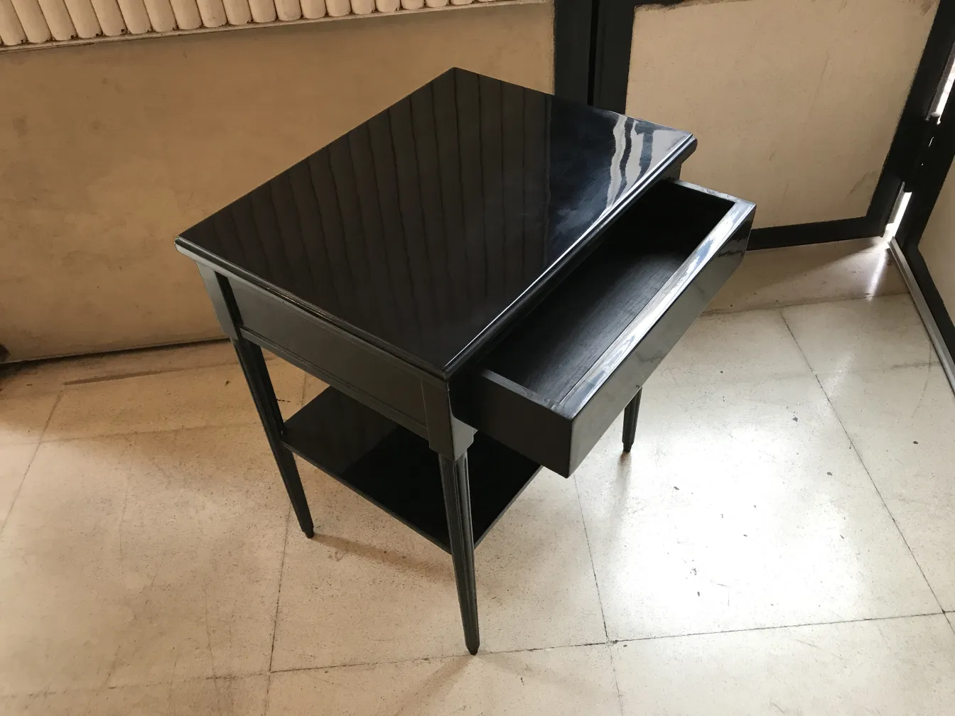 comodino antico con superficie lucida e cassetto