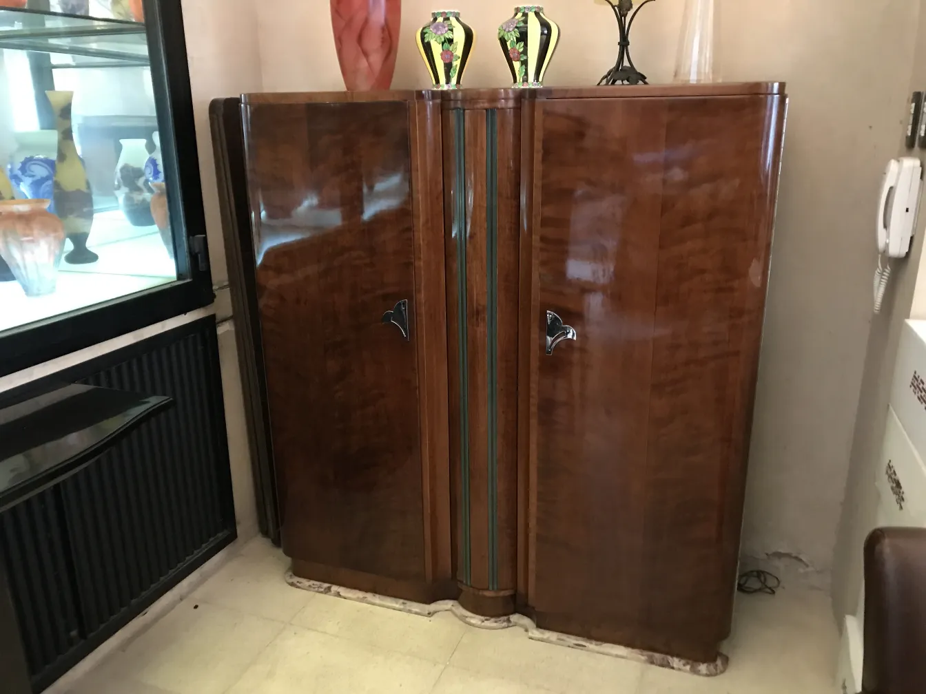 estante de livros antigo com acabamento brilhante e detalhes decorativos, em um ambiente de antiguidades