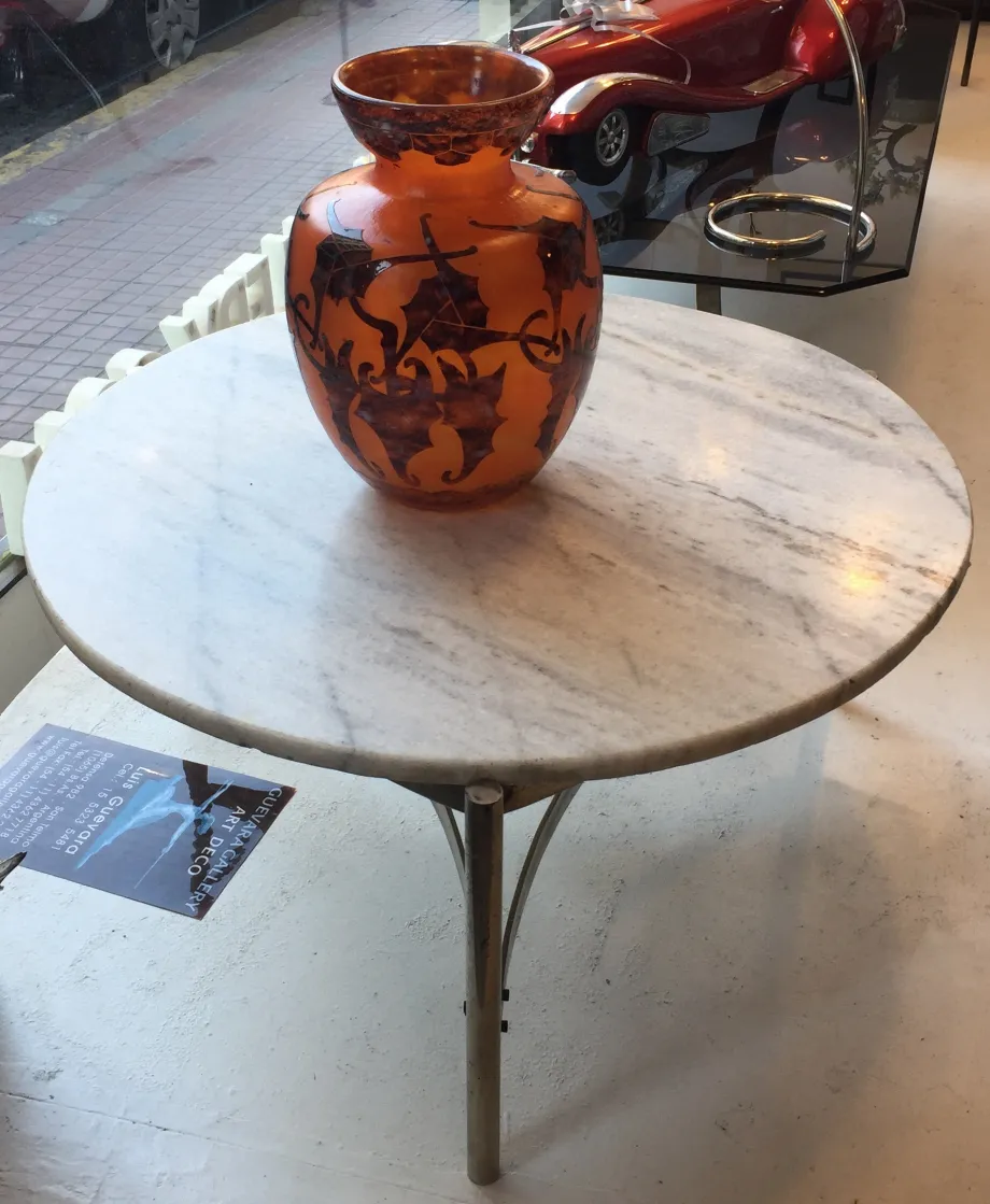 Tavolino da caffè antico in stile Art Deco con un vaso arancione sopra.