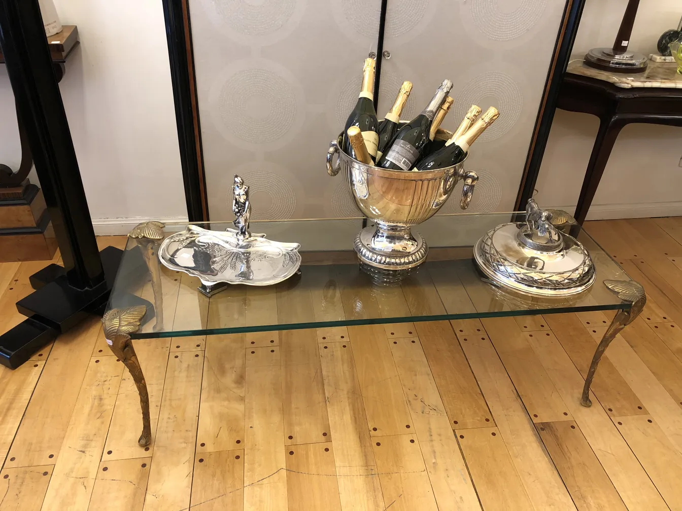 Maison Charles 古董茶几，配有托盘、香槟桶和装饰配件，放在木地板上。