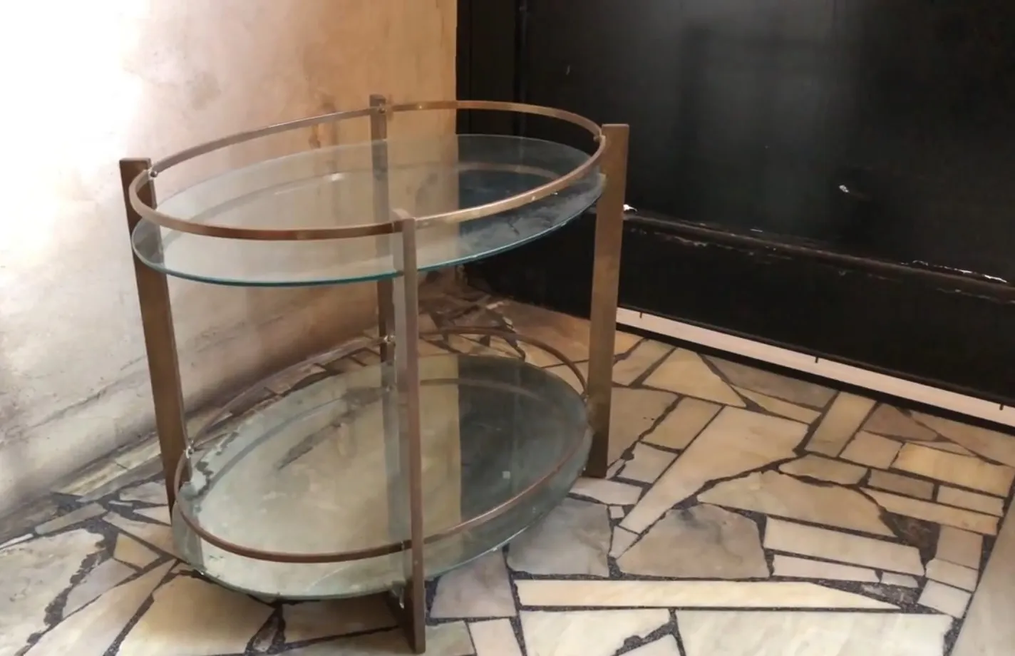 Mueble bar antiguo de vidrio con base metálica en ambiente elegante.