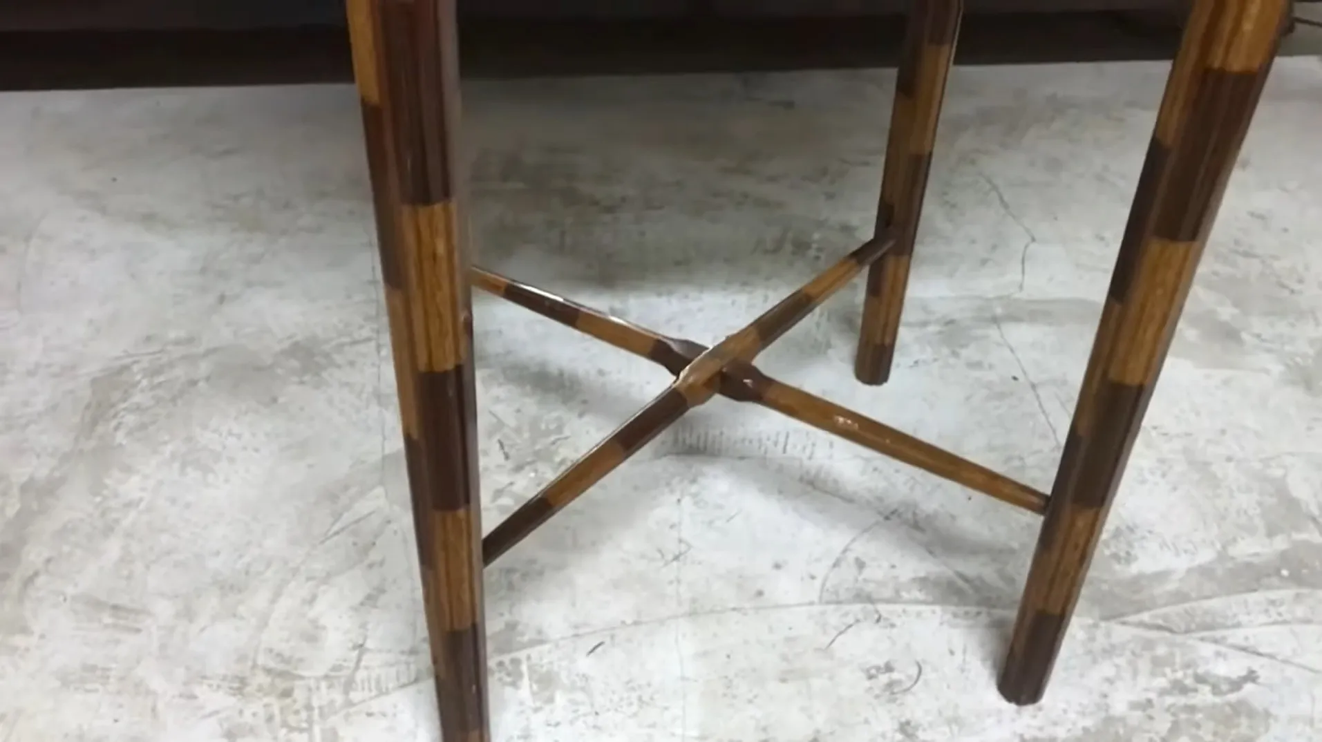 vue latérale d'une ancienne petite table avec des pieds croisés sur un fond clair