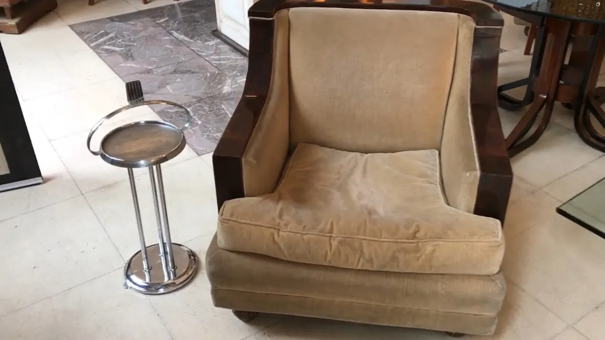 Antique small table with an elegant design and functional space next to an armchair.