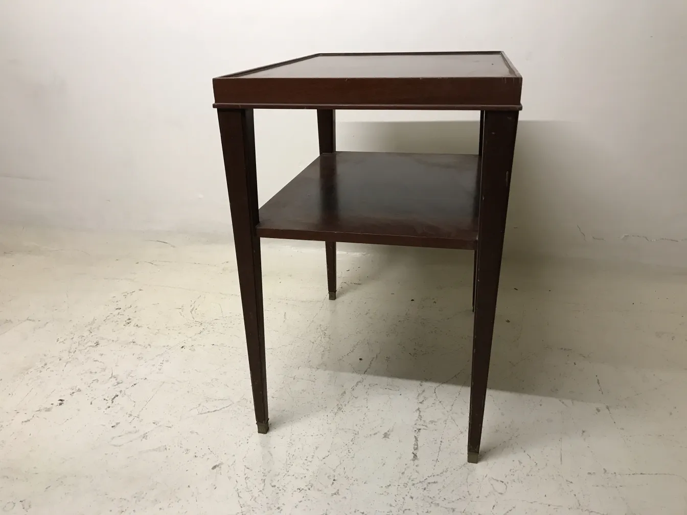 Mesa antigua estilo Art Deco con estante de nivel inferior, ambiente sencillo.