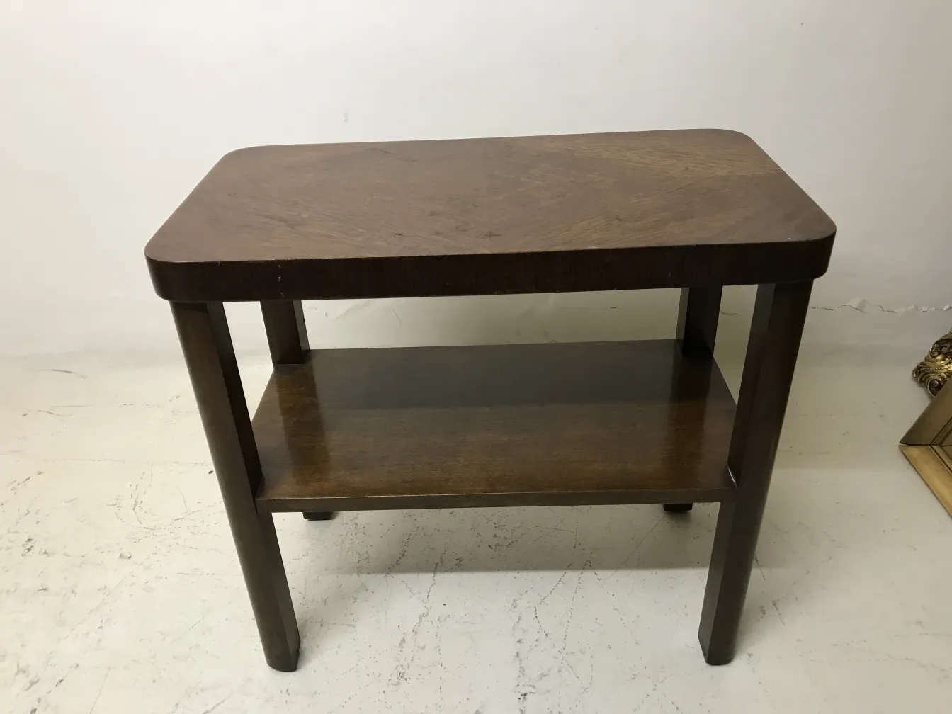 Mesa antigua de estilo Art Deco con estante inferior, en tono marrón.