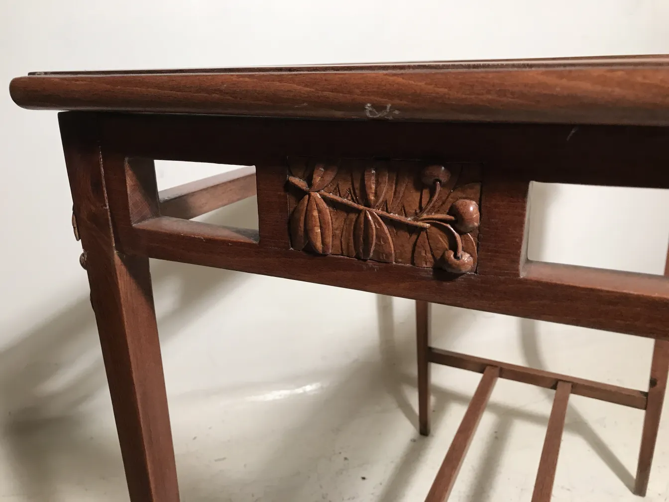 Mesa antigua de madera con tallados florales, ambiente neutro.