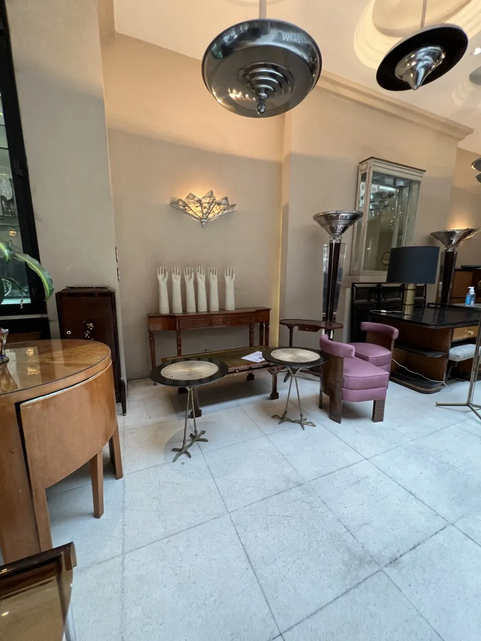 Dos mesitas de antigüedades con decoración clara en un ambiente elegante, junto a otros muebles.