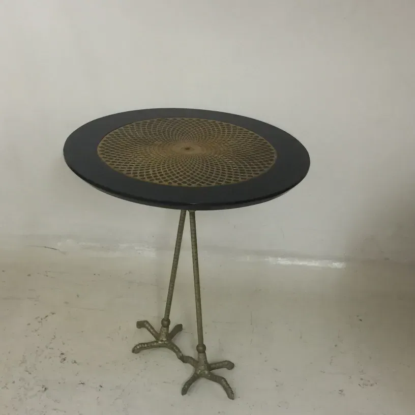 Deux petites tables anciennes avec un motif décoratif et des pieds uniques dans un cadre minimaliste.