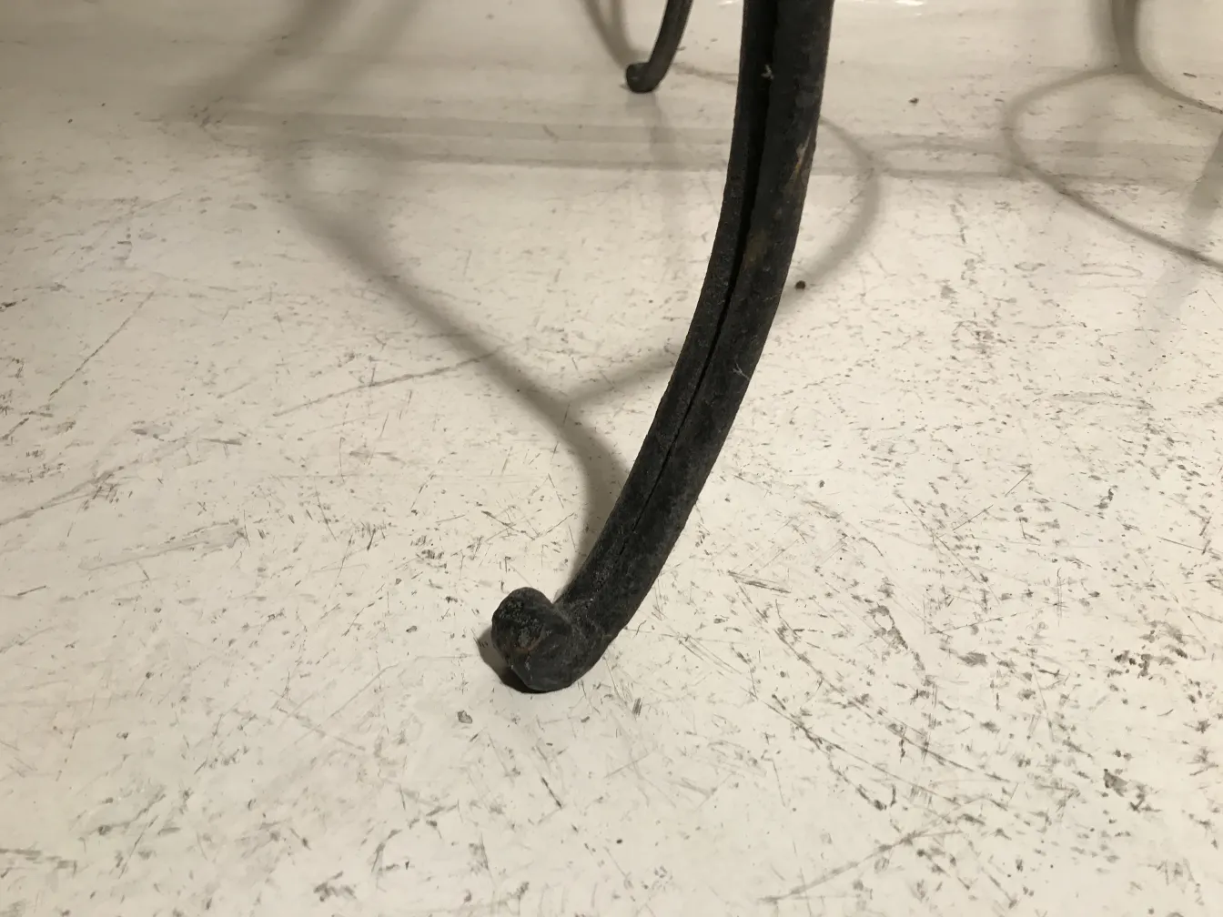 Mesa antiga com patas decorativas em um ambiente de jardim