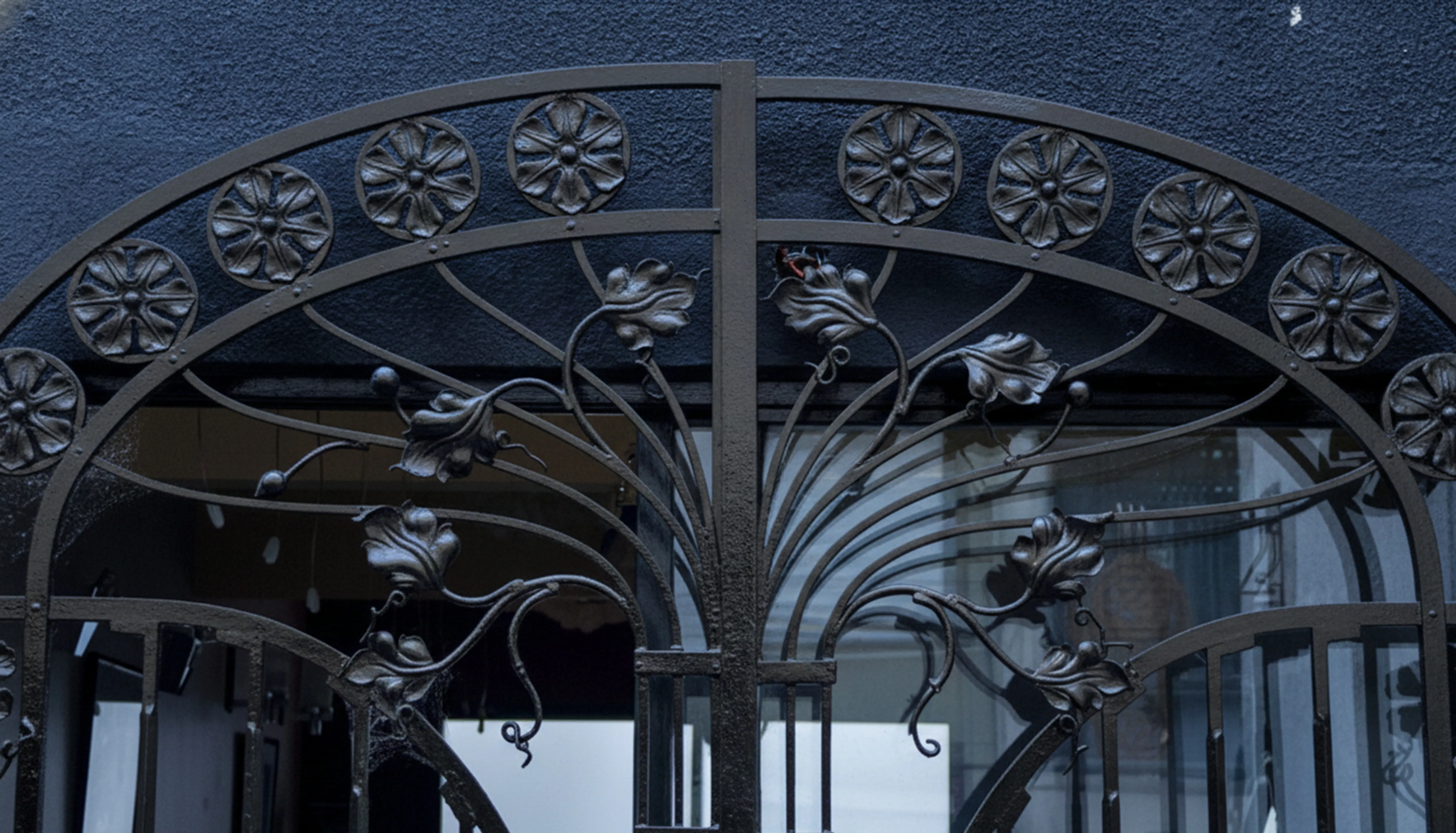 Portón antiguo adornado con detalles florales y un fondo oscuro.