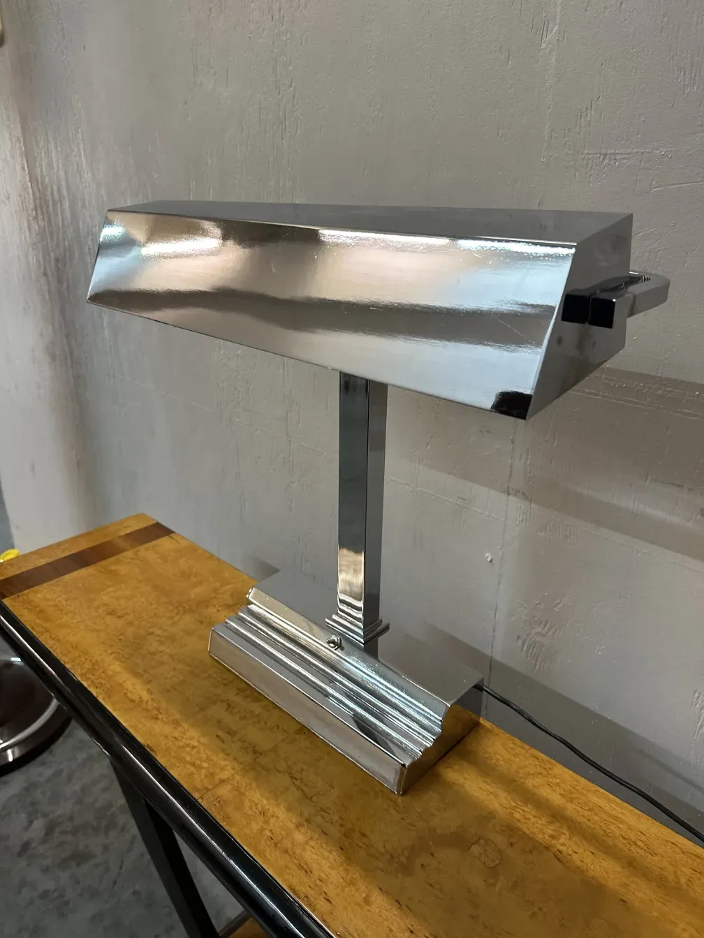 luminária de mesa art deco com base cromada sobre uma mesa de madeira