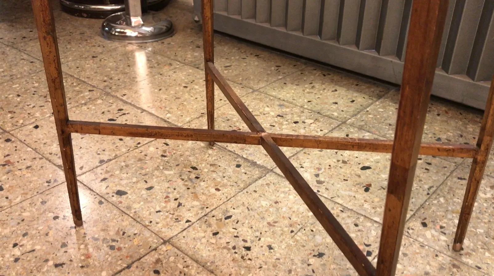 Antiker Tisch mit gekreuzten Beinen, modernes Umfeld.