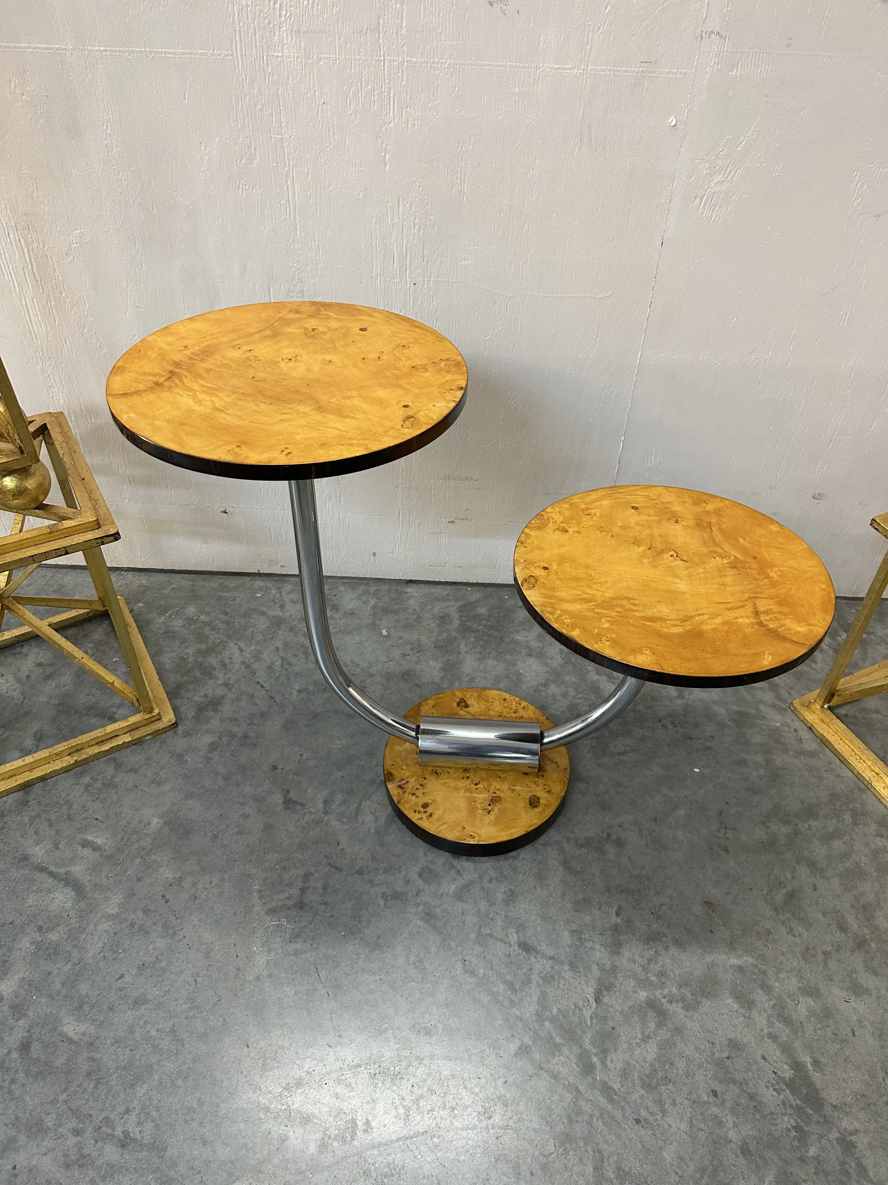 Ancienne petite table avec deux surfaces rondes et base métallique dans un environnement moderne.