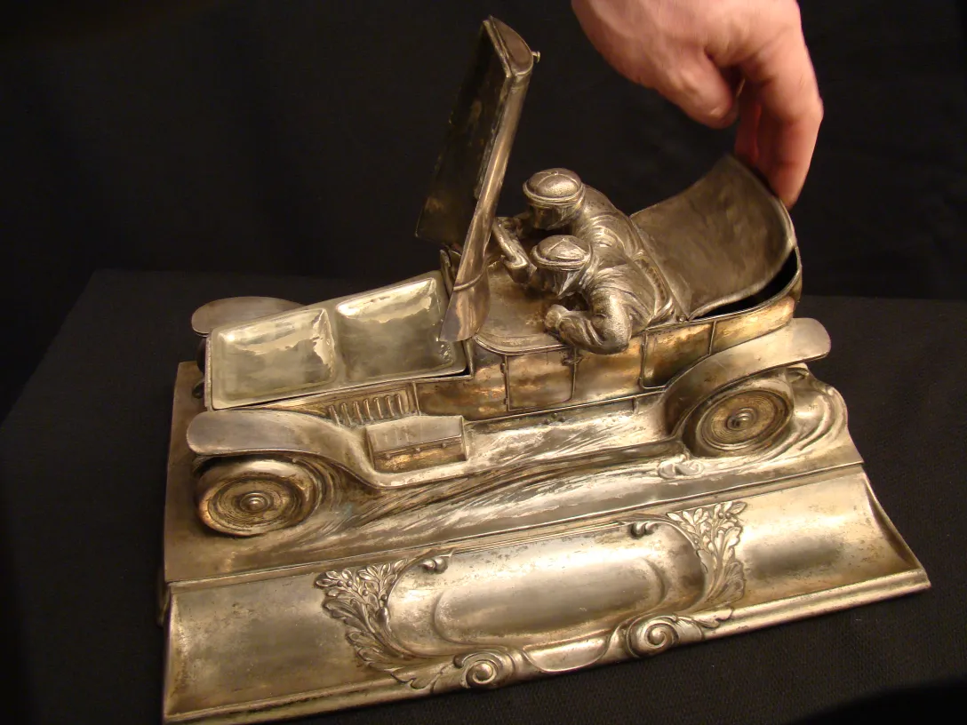 Antikes Tintenfass WMF in Form eines Autos mit zwei Figuren.