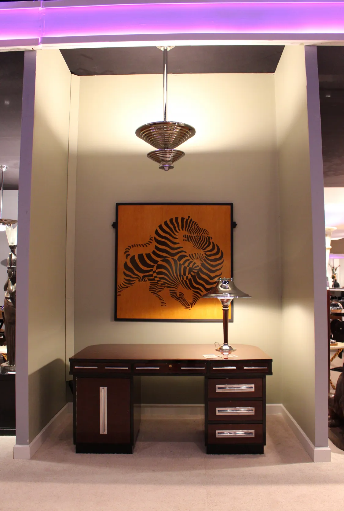 Ancienne lustre de style art déco, avec un design attrayant et une œuvre d'art colorée en arrière-plan.