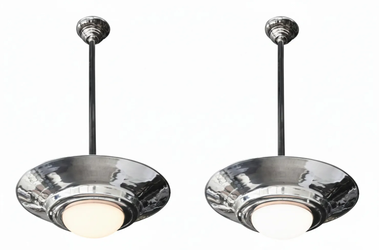 Set di quattro lampade a sospensione antiche art déco che illuminano uno spazio elegante.