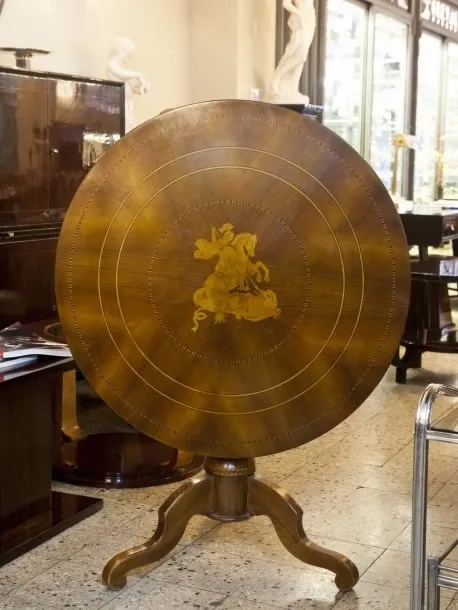 Mesa redonda antiga com design decorativo e pernas elegantes em um ambiente sofisticado.